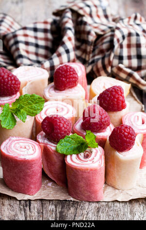 Gerollt Milch und Himbeer Pfannkuchen am Holztisch Stockfoto