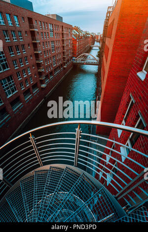 Wendeltreppen, die in der Speicherstadt von der Kanalseite mit roten Backsteinbauten der Speicherstadt in Hamburg. Blaue Stunde Stockfoto