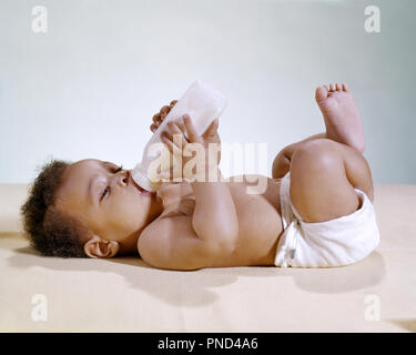 1960 AFRICAN AMERICAN BABY LIEGEND AUF DER RÜCKSEITE das Trinken aus der Flasche - kn 738 HAR 001 HARS JUGENDLICHE DURSTIG HAR 001 ALTMODISCH afrikanische Amerikaner Stockfoto