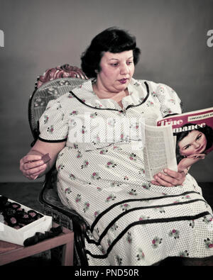 1950 übergewichtige übergewichtige Frau sitzt essen Schachtel Schokolade Süßigkeiten LESEN FILM FAN MAGAZIN - Ks 38469 FRT001 HARS VENTILATOR PERSONEN DISZIPLIN TRAURIGKEIT BRUNETTE SELBST VERSUCHUNG TRÄUME WAHL ERHOLUNG DER DESTRUKTIVEN ÜBER KONZEPTIONELLE PROBLEM wahre Mitte - Mitte - ERWACHSENEN FRAU OBSESSIVE KAUKASISCHEN ETHNIE ALTMODISCH Stockfoto