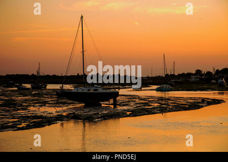 Sonnenuntergang bei Leigh On Sea Sümpfe mit Reflexionen im Wasser und Boote. Stockfoto