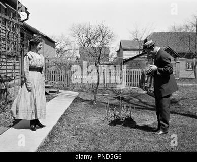 1900s 1910s DREHEN DES 20. JAHRHUNDERTS MANN, BILD DER FRAU, DIE VOR DEM HAUS-o3633 LEF 001 HARS junger Erwachsener Fotos drehen Fotos LIFESTYLE FRAUEN VERHEIRATET LÄNDLICHEN EHEPARTNER EHEMÄNNER GROWNUP HOME LEBENSQUALITÄT HORIZONTAL KOPIEREN RAUM VOLLER LÄNGE DAMEN PERSONEN KAMERAS MÄNNER KAMERAMANN B&W MÄNNER UND FRAUEN PARTNER BILDER FOTOGRAFEN FREIZEITAKTIVITÄTEN DREHEN DES 20. JAHRHUNDERTS GENTLEMAN UND KOLLEGEN DER JAHRHUNDERTWENDE DES FOTOGRAFISCHEN MANLY FOTOGRAFIE KAMERALEUTE PARTNER MITEINANDER FRAUEN JUNGE ERWACHSENE MANN junger Erwachsener FRAU SCHWARZ UND WEISS KAUKASISCHEN ETHNIE ALTMODISCH Stockfoto