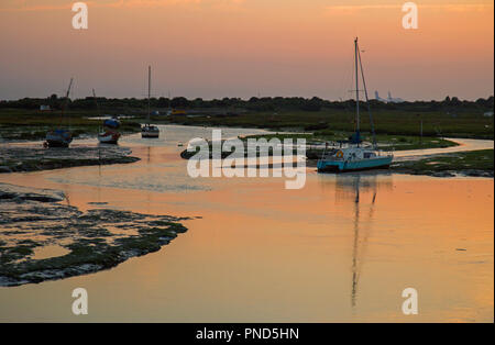 Sonnenuntergang bei Leigh On Sea Sümpfe mit Reflexionen im Wasser und Boote. Stockfoto