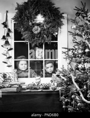 1950er Jahre Kinder, ein Mädchen, zwei Jungen auf der Suche DURCH DAS FENSTER AM WEIHNACHTSBAUM MIT eingepackte Geschenke KRANZ AUFHÄNGEN OBEN x325 HAR 001 HARS NOSTALGIE BRUDER OLD FASHION SCHWESTER 1 durch jugendliches Gesicht KRANZ FREUEN FREUDE LIFESTYLE FEIER FRAUEN BROTHERS STUDIO SHOT HOME LEBEN MÄNNER GESCHWISTER GESCHENKE SCHWESTERN AUSDRÜCKE B&W TRÄUME GLÜCK KOPF UND SCHULTERN FRÖHLICHE FRÖHLICHE SPANNUNG IN ERWARTUNG GESCHWISTER LÄCHELN DEZEMBER KONZEPTIONELLE DEZEMBER 25 freudige Besuch fröhliche JUGENDLICHE MITEINANDER SCHWARZ UND WEISS KAUKASISCHEN ETHNIE HAR 001 ALTMODISCH Stockfoto