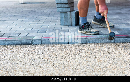 Festlegung grauer Beton Pflastersteine in Haus Hof Einfahrt, Terrasse. Professionelle Mitarbeiter Maurer Einbau einer neuen Fliesen oder Platten für Auffahrt, Stockfoto