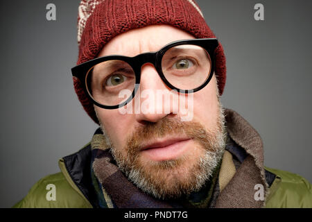 Close up Portrait von europeam Mann mittleren Alters in den lustigen warme Mütze und Brille bemerken versteckte Kamera. Jemand ist Spionage nach mir wirklich. Stockfoto