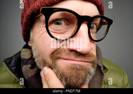 Close up Portrait von europeam Mann mittleren Alters in den lustigen warme Mütze und Brille bemerken versteckte Kamera. Jemand ist Spionage nach mir wirklich. Stockfoto