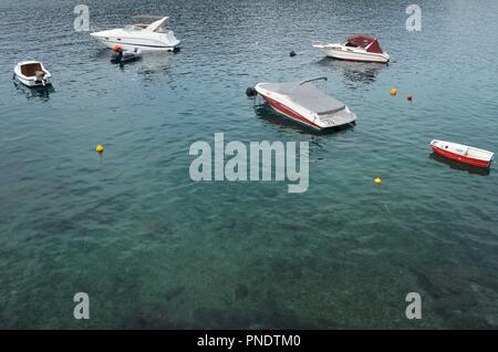 Kleine Boote schwimmend im schönen Türkis und schwarz gefärbten Wasser in Rabac in Kroatien Stockfoto