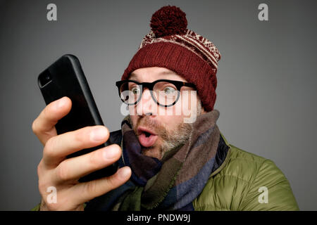 Close up Portrait von lustigen jungen Mann ist überrascht und verwirrt Lesen sms oder e-mail schockiert Stockfoto