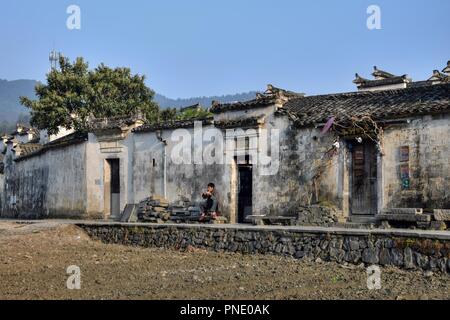 XIDI, Provinz Anhui, China - ca. Oktober 2017: Ein Mann ist das Essen vor einem Haus in Xidi, einem kleinen alten Dorf in der Nähe des gelben Berge. Stockfoto