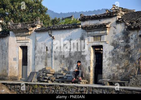 XIDI, Provinz Anhui, China - ca. Oktober 2017: Ein Mann ist das Essen vor einem Haus in Xidi, einem kleinen alten Dorf in der Nähe des gelben Berge. Stockfoto