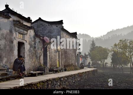 XIDI, Provinz Anhui, China - ca. Oktober 2017: Ein Mann ist das Essen vor einem Haus in Xidi, einem kleinen alten Dorf in der Nähe des gelben Berge. Stockfoto