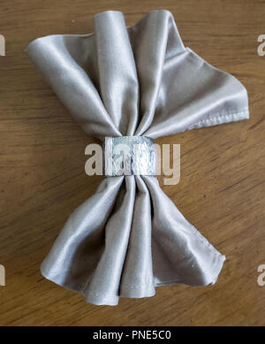 Golden serviette Bogen mit Silber Ring fancy Folding für Urlaub Holz Tisch Hintergrund Stockfoto
