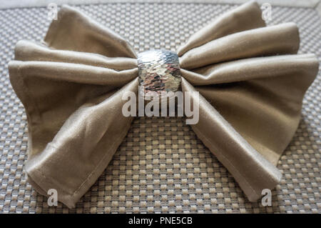 Golden serviette Bogen mit Silber Ring fancy Folding für Urlaub gold Hintergrund Stockfoto