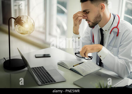 Ärzte sind die ernsten Gesichter und gestresst von der Arbeit. Der Arzt ist ein Gefühl der Kopfschmerzen bei der Arbeit und das Gefühl, in der Behandlung des Patienten betont. Stockfoto