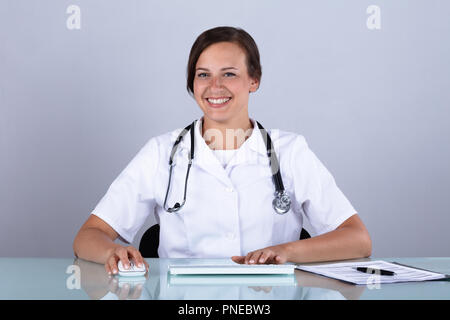 Porträt eines lächelnden jungen Ärztin in der Klinik sitzen Stockfoto