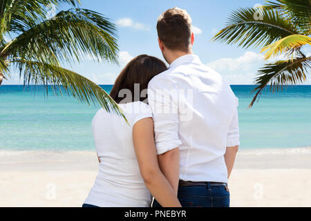 Rückansicht eines jungen Paares am tropischen Strand stehend Stockfoto