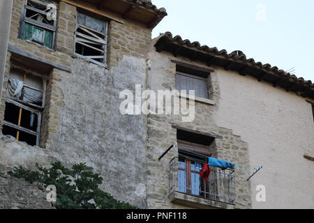 Fünf kleine Fenster mit alten schäbigen Fensterläden aus Holz, Geländer und zerbrochene Gläser auf einen Stein grau houes in Frago, einer kleinen Stadt in Aragon, Spanien Stockfoto