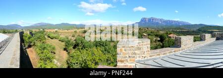 Eine Landschaft mit blauem Himmel, einige Wolken, die mittelalterlichen Mauern und die Peña Montañesa Bergmassiv im Spanischen Pyrenäen Stockfoto