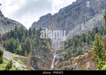 Eine Landschaft mit einem Wasserfall in den Bergen von Kiefern und Tannen wald und einen blauen Himmel mit einigen Wolken im Ordesa-tal, Spanien umgeben Stockfoto