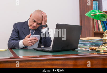 Der Mann am Schreibtisch, betrachten Sie Ihre i Pad/Tablet, in seinem Büro. Stockfoto