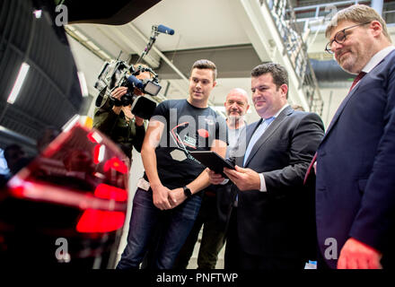 21. September 2018, Niedersachsen, Wolfsburg: Ralph Linde (L-R), Leiter der Volkswagen Group Academy, Hubertus Heil (SPD), Bundesminister für Arbeit und Soziales, Bernd Osterloh, Leiter der VW-Betriebsrat, und Patrick Schilling, Elektroniker für Automatisierungstechnik, betrachten Sie eine VW Golf GTI durch Auszubildende ausgestattet als Teil der Präsentation der neuen Fakultät 73 "qualifizierungsoffensive. E-Autos, Digitalisierung und Vernetzung - das sind die großen Trends in der Automobilindustrie. Die Branche braucht in erster Linie Software Experten für diese, während die Mitarbeiter in den Motor ein Stockfoto