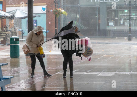 Stadtzentrum Warrington, Cheshire, England, Großbritannien - 21 September 2018 - Wetter - am späten Nachmittag und die Windstärke Winde der Sturm Bronagh, der zweite Sturm der britischen Winter innerhalb von Tagen, erhöhten ihre Intensität, mit Böen von über 50 mph in Warrington, Cheshire. Bild: Menschen kämpfen, um ihre Schirme richtig in den Wind zu halten. Stockfoto