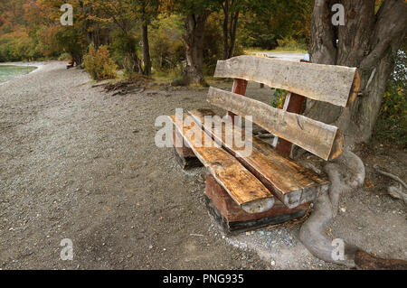 Rustikale Holzbank aus Holz Protokolle am Ufer des Sees unter Falllaub in Tierra del Fuego National Park, Patagonien, Argentinien Stockfoto