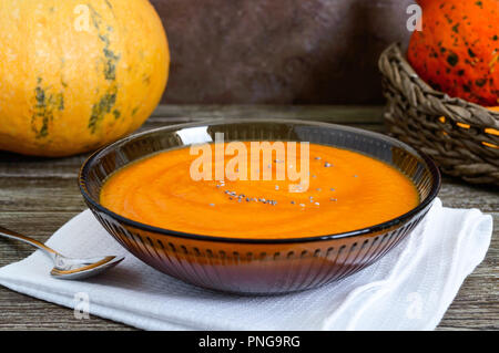 Zarte Kürbispüree in einem schwarzen Glas Schüssel auf einen hölzernen Tisch. Stockfoto