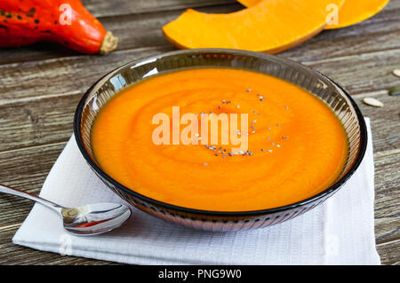 Zarte Kürbispüree in einem schwarzen Glas Schüssel auf einen hölzernen Tisch. Stockfoto