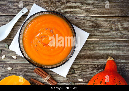 Zarte Kürbispüree in einem schwarzen Glas Schüssel auf einen hölzernen Tisch. Ansicht von oben. Stockfoto