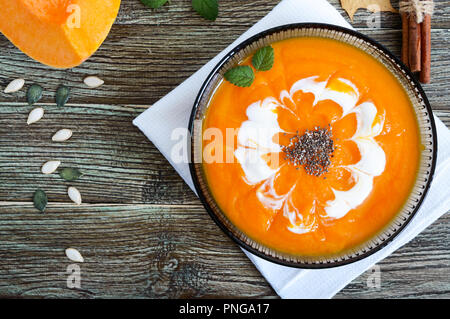 Zarte Kürbispüree mit Sahne und Chia Samen in ein schwarzes Glas Schüssel auf einen hölzernen Tisch. Ansicht von oben. Stockfoto