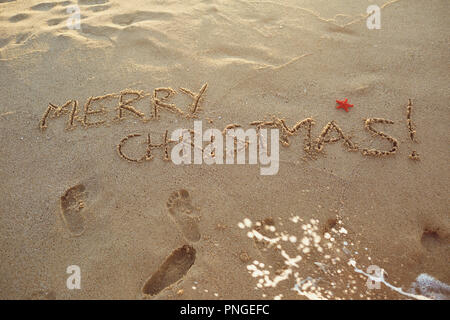 Die aufschrift Frohe Weihnachten auf dem Sand am Strand. Stockfoto