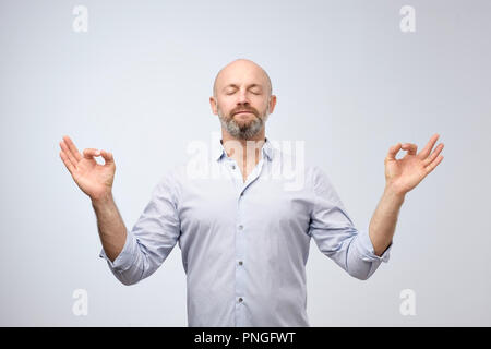 Yoga und Meditation im Büro während der Arbeit Tag. Stattliche glatzköpfige Mann mit Borsten halten die Augen geschlossen während der Meditation, entspannte Gefühl, ruhige, friedliche Ho Stockfoto
