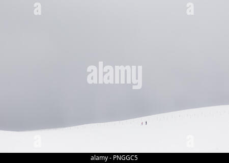 Ein sehr minimalistisches Blick auf zwei weit entfernte Menschen über einen Berg von Schnee bedeckt. Stockfoto
