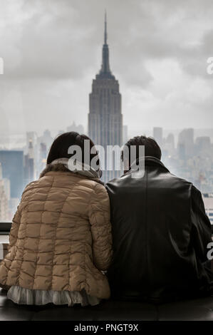 New York, USA. 05. Oktober 2008. Ein paar sitzen an einem Fenster an der Aussicht auf das Empire State Building und Manhattan in New York, USA Stockfoto