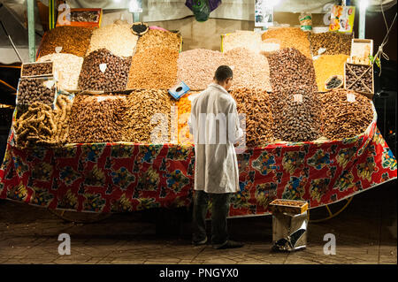 25-02-11. Marrakesch, Marokko. Inhaber verkauf Termine stall und getrocknete Aprikosen in Jemaa el-Fna in der Nacht. Es ist ein öffentlicher Platz mit kleinen merchan Stockfoto