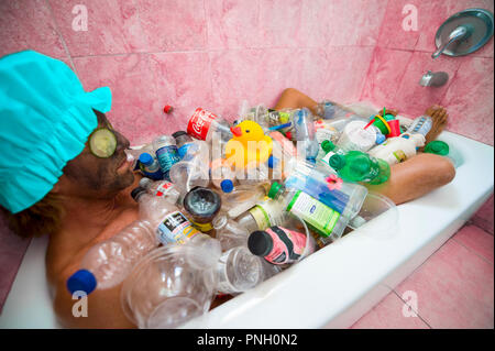 MIAMI, USA - ca. Juli 2018: Mann baden in einer Wanne mit plastik Müll als eine Nachricht an die Gefahren der Umweltverschmutzung konfrontiert Stockfoto