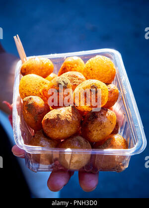 Eine weibliche Hand, die eine Schachtel Lokma, typisch türkischen verzetteln. Auch bekannt als Arabisch, Griechisch oder Loqma Luqaimat Loukoumades oder loukoumas, Persische Bamiyeh. Stockfoto