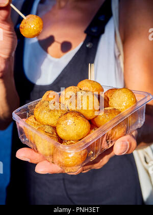 Eine weibliche Hand, die eine Schachtel Lokma, typisch türkischen verzetteln. Auch bekannt als Arabisch, Griechisch oder Loqma Luqaimat Loukoumades oder loukoumas, Persische Bamiyeh. Stockfoto