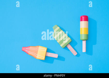 Drei Holzspielzeug eis Lutscher Eis am Stiel auf einem Pastell-blaue Hintergrund mit Platz für Text mit minimalistischen Zusammensetzung Stockfoto