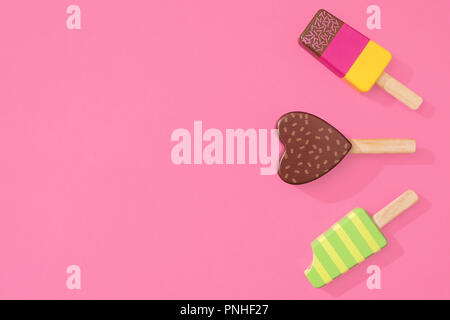 Drei Holzspielzeug ice lollipop Eis am Stiel auf einem Pastell rosa Hintergrund mit Platz für Text Stockfoto