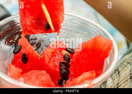 Stücke von saftig roten Wassermelone mit Knochen in einem Plastikbecher. Close-up. Stockfoto