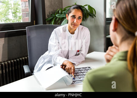 Junge indische Ärztin diskutieren CT Scans mit einer weiblichen Patienten. Mittellange Aufnahme. Stockfoto