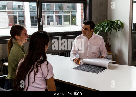 Health Professional lächelnd und ein Gespräch mit einem Paar der jungen Patienten. Mittellange Aufnahme. Stockfoto