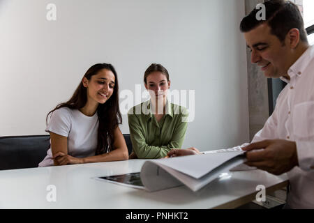 Health Professional lächelnd und ein Gespräch mit einem Paar der jungen Patienten. Mittellange Aufnahme. Stockfoto