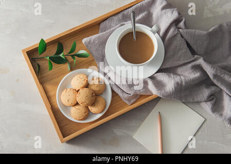 Tee mit Cookies in weißen Schale Platte mit Papier und Bleistift Stockfoto
