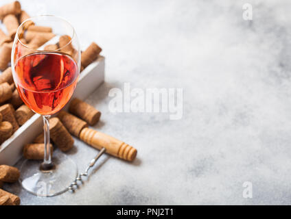 Glas rosa Rose Wein mit Box von Korken und Korkenzieher Dosenöffner auf Stein Küchentisch Hintergrund. Ansicht von oben. Stockfoto