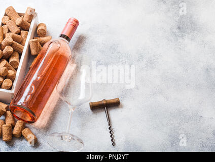 Flasche und Gläser pink rose Wein mit Box von Korken und Korkenzieher Dosenöffner auf Stein Küchentisch Hintergrund. Ansicht von oben. Stockfoto