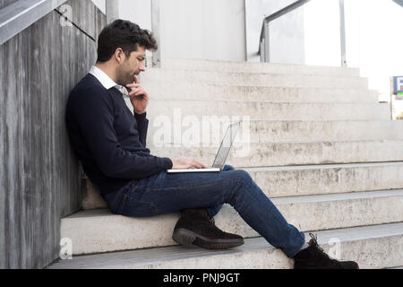 Junger Mann mit Computer und Zweifel Stockfoto